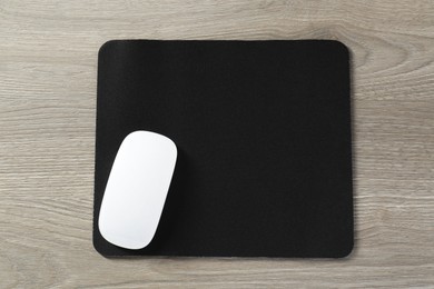 Wireless mouse and mousepad on wooden table, top view