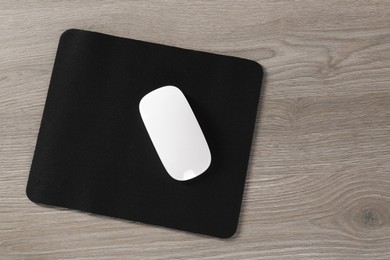 Wireless mouse and mousepad on wooden table, top view. Space for text