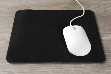 Photo of Wired mouse and mousepad on wooden table