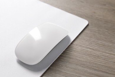 Wireless mouse and mousepad on wooden table, closeup. Space for text