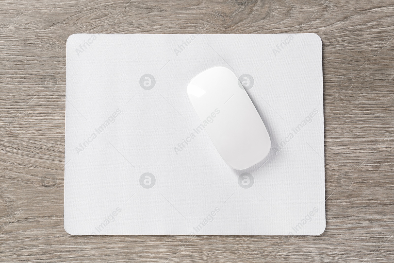 Photo of Wireless mouse and mousepad on wooden table, top view