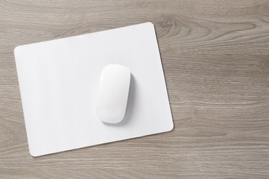 Wireless mouse and mousepad on wooden table, top view