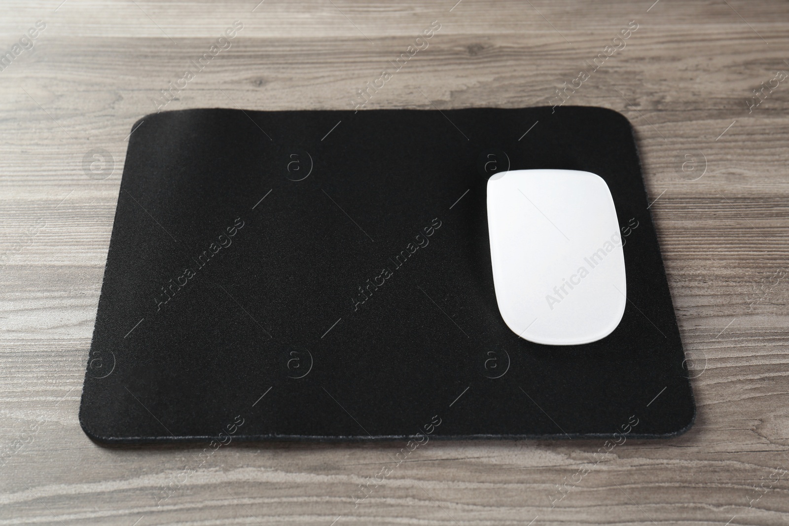 Photo of Wireless mouse and mousepad on wooden table