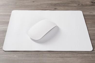 Photo of Wireless mouse and mousepad on wooden table