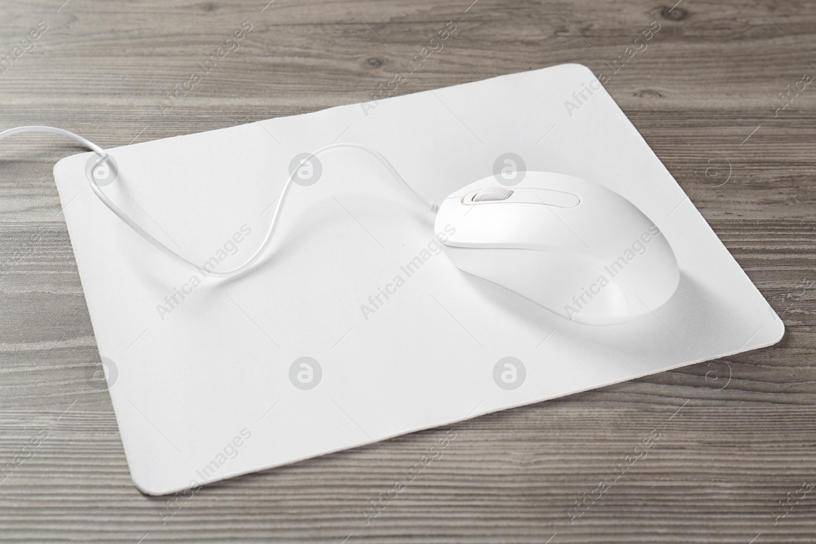 Photo of Wired mouse and mousepad on wooden table