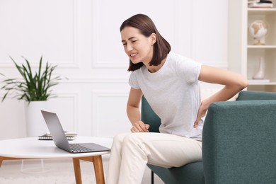 Woman suffering from back pain at home. Symptom of poor posture