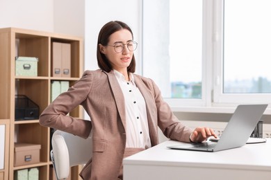 Photo of Woman suffering from back pain in office. Symptom of poor posture