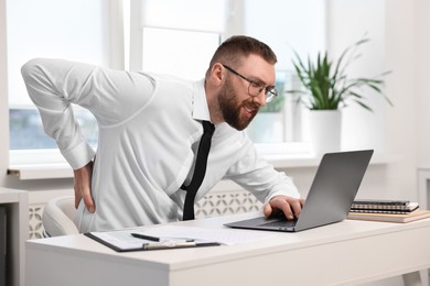 Man suffering from back pain in office. Symptom of poor posture