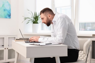 Photo of Man with poor posture working in office