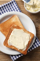 Delicious toasted bread slices with butter on wooden table, flat lay