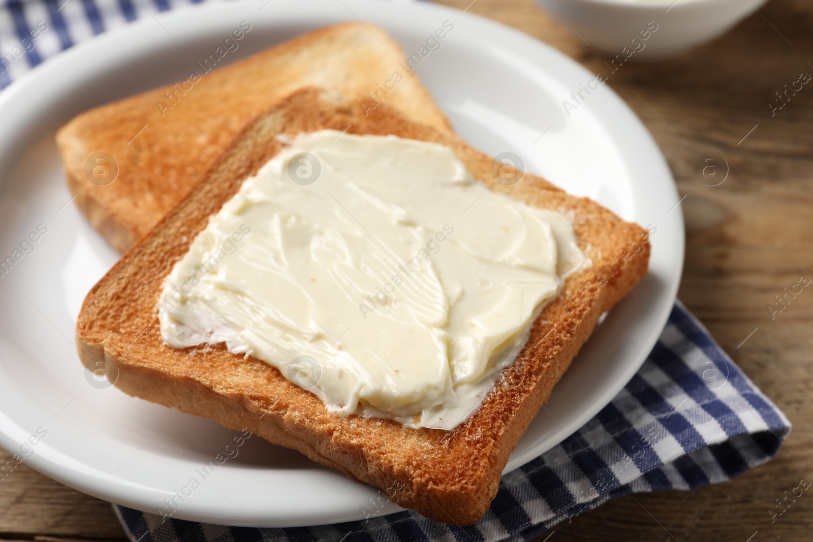 Photo of Delicious toasted bread slices with butter on wooden table, closeup