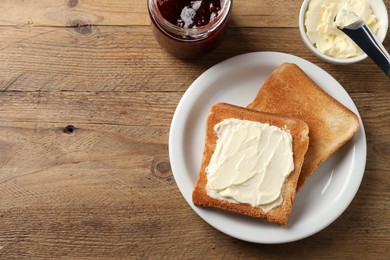 Photo of Delicious toasted bread slices with butter served on wooden table, flat lay. Space for text