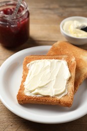 Photo of Delicious toasted bread slices with butter served on wooden table, closeup