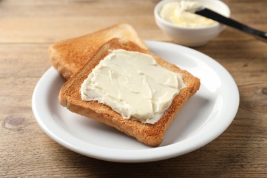 Photo of Delicious toasted bread slices with butter on wooden table, closeup