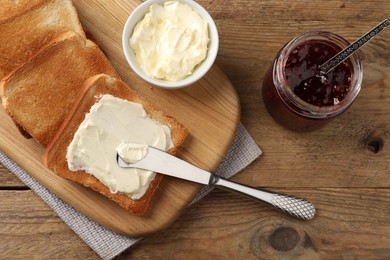 Delicious toasted bread slices with butter served on wooden table, flat lay