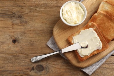 Photo of Delicious toasted bread slices with butter and knife on wooden table, flat lay. Space for text