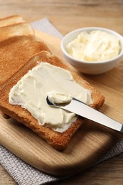 Delicious toasted bread slices with butter and knife on wooden table, closeup