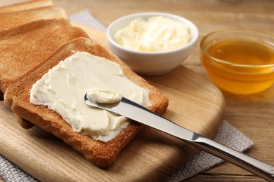 Photo of Delicious toasted bread slices with butter served on wooden table, closeup