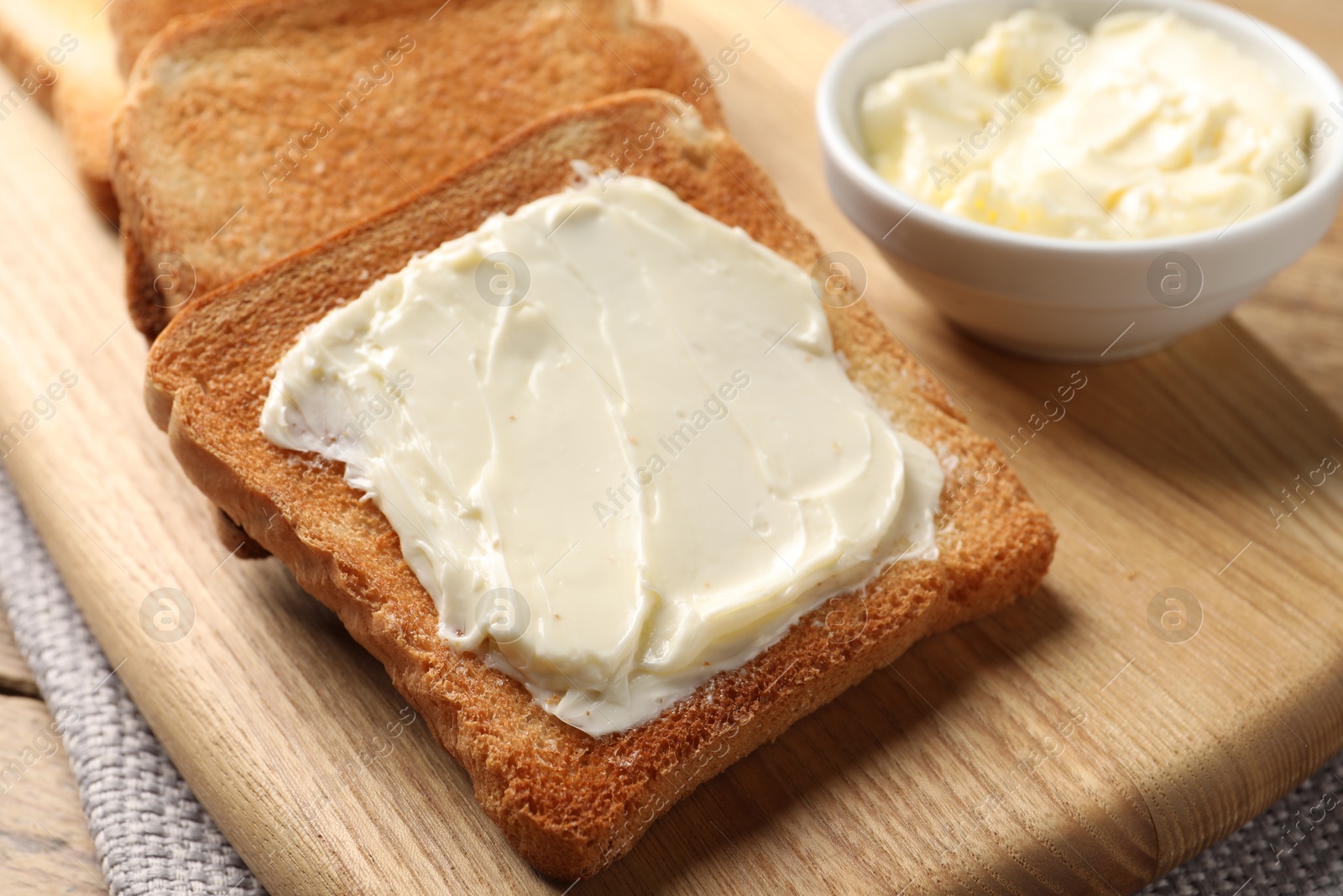 Photo of Delicious toasted bread slices with butter on table, closeup