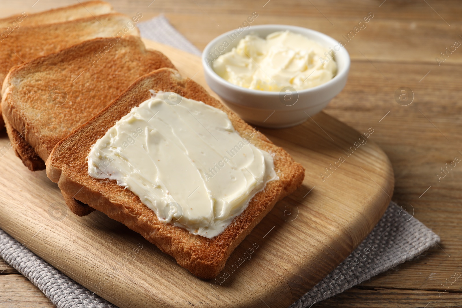 Photo of Delicious toasted bread slices with butter on wooden table