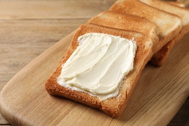 Photo of Delicious toasted bread slices with butter on wooden table, closeup