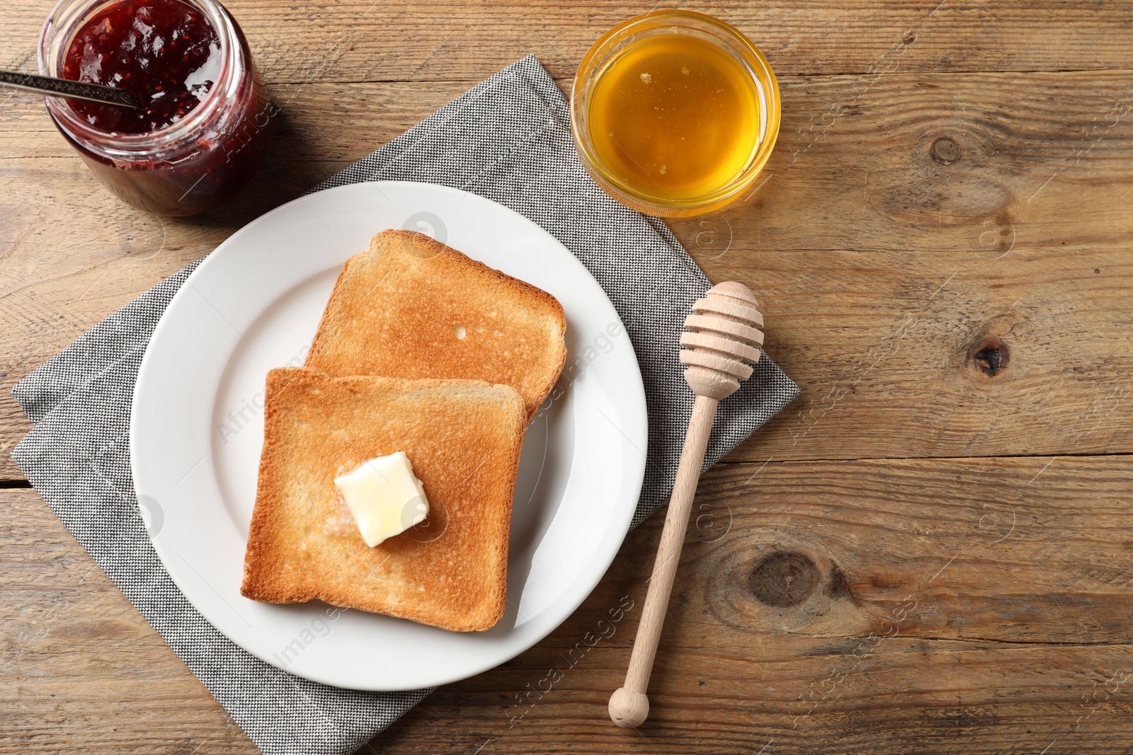 Photo of Delicious toasted bread slices with butter served on wooden table, flat lay