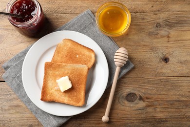 Photo of Delicious toasted bread slices with butter served on wooden table, flat lay