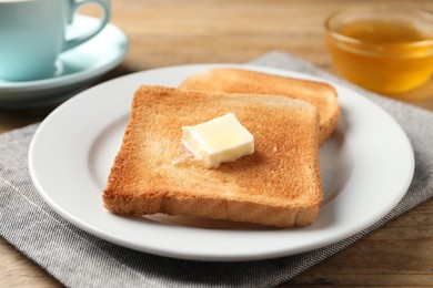 Photo of Delicious toasted bread slices with butter on wooden table, closeup