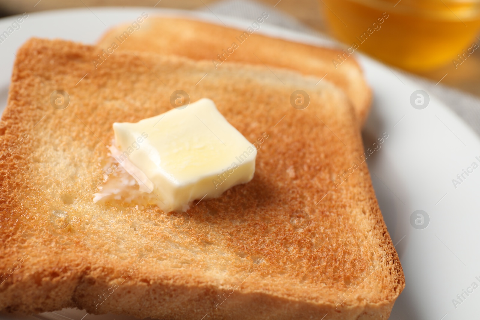 Photo of Delicious toasted bread slices with butter on table, closeup