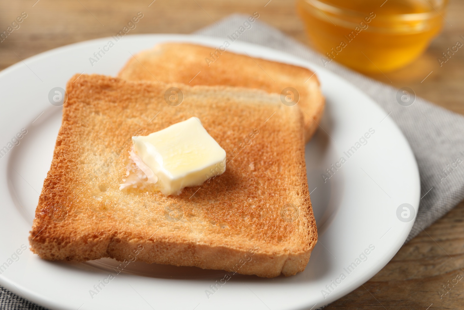 Photo of Delicious toasted bread slices with butter on table, closeup