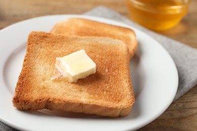 Delicious toasted bread slices with butter on table, closeup