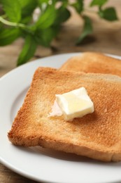 Photo of Delicious toasted bread slices with butter on table, closeup