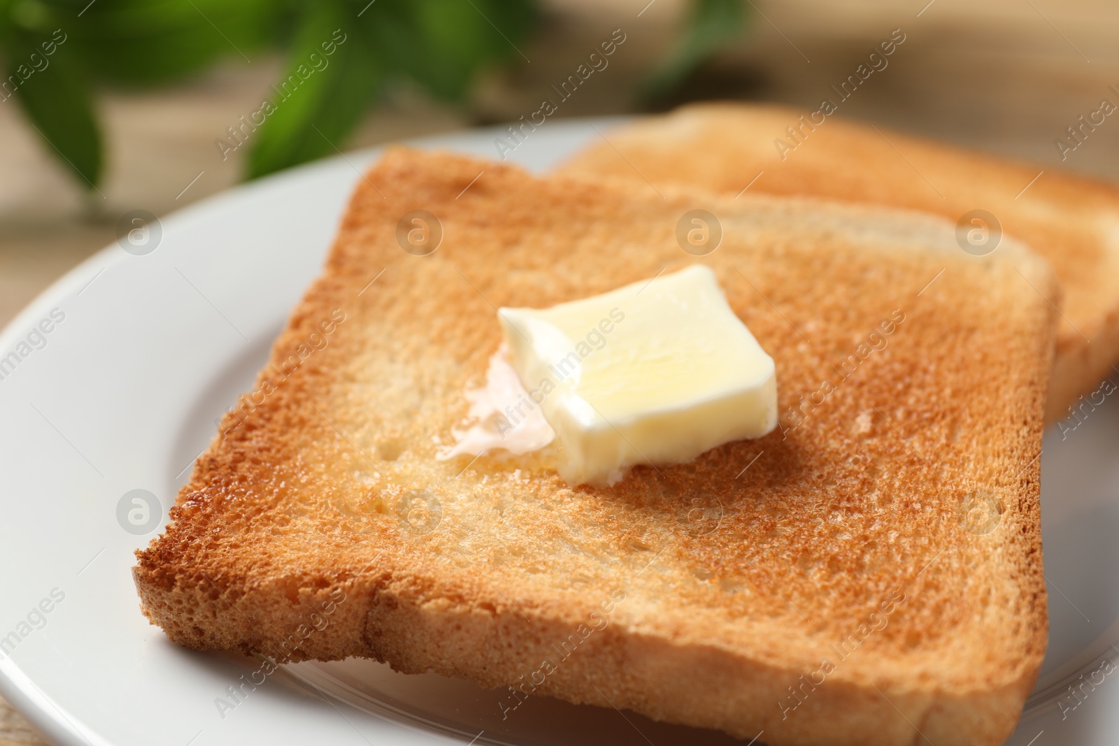 Photo of Delicious toasted bread slices with butter on table, closeup