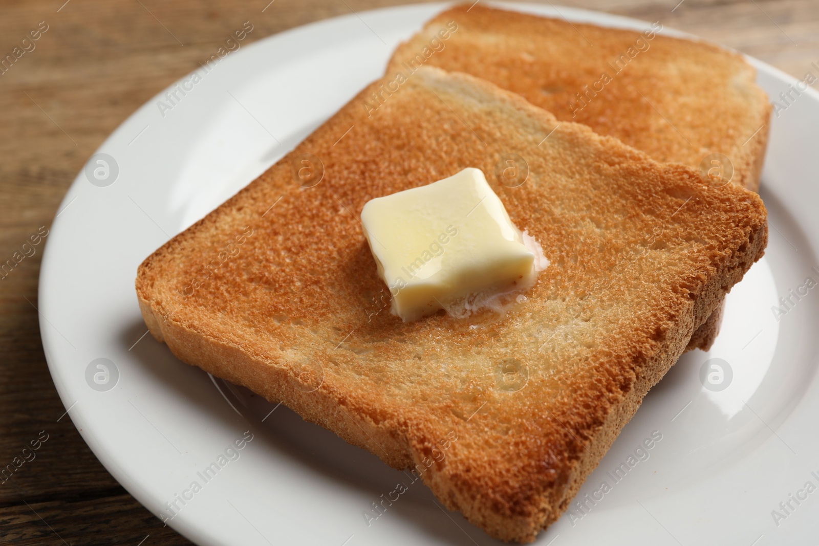 Photo of Delicious toasted bread slices with butter on table, closeup