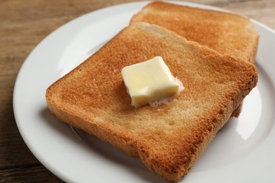 Delicious toasted bread slices with butter on table, closeup