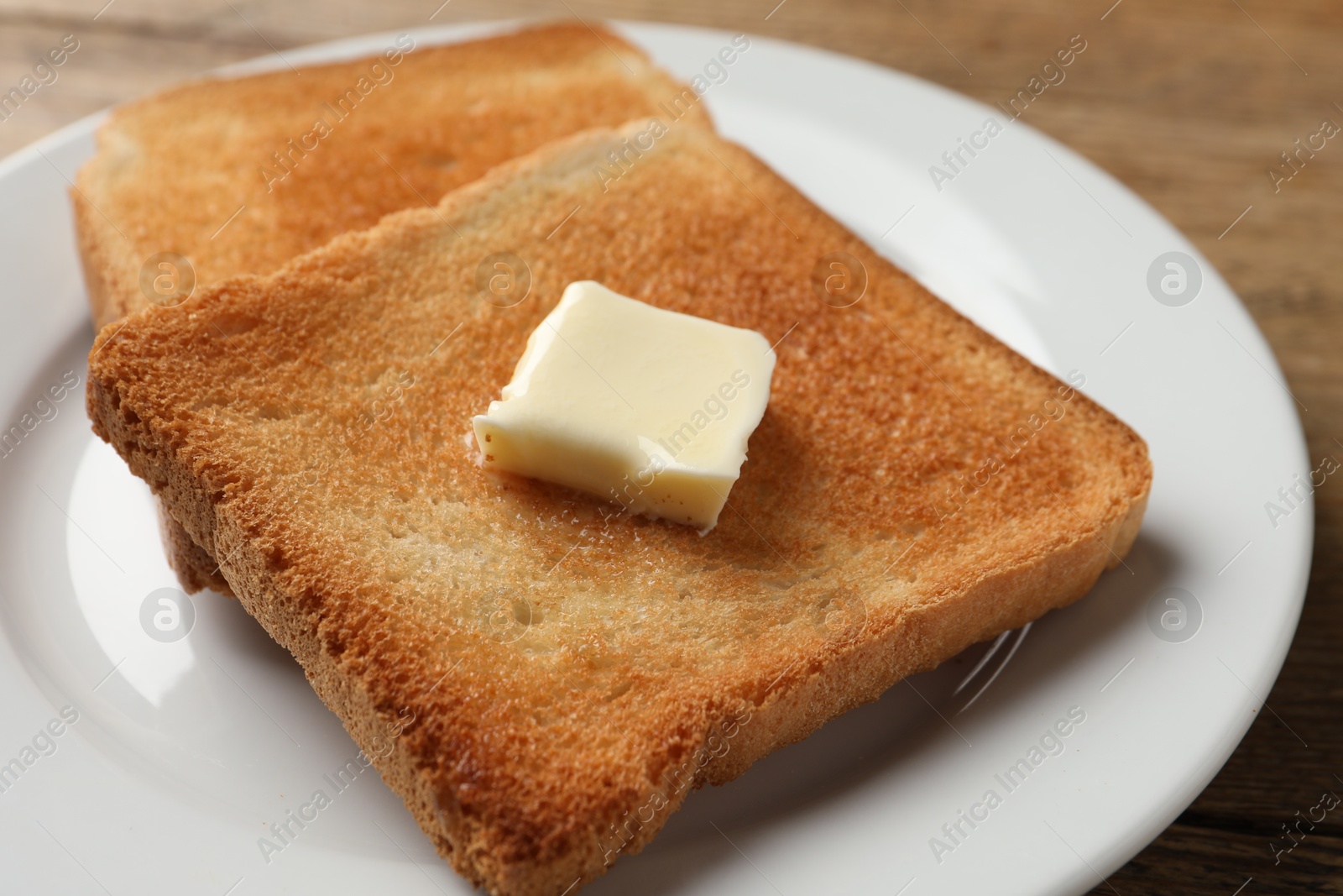 Photo of Delicious toasted bread slices with butter on table, closeup