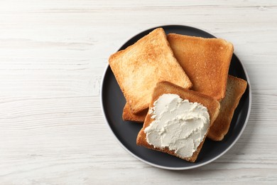 Delicious toasted bread slices with cream cheese on white wooden table, top view. Space for text