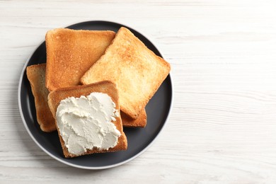 Delicious toasted bread slices with cream cheese on white wooden table, top view. Space for text