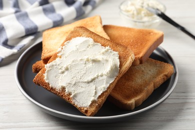 Photo of Delicious toasted bread slices with cream cheese on white wooden table