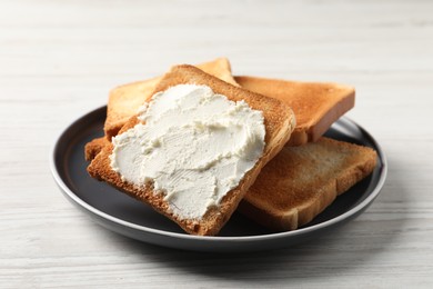 Photo of Delicious toasted bread slices with cream cheese on white wooden table