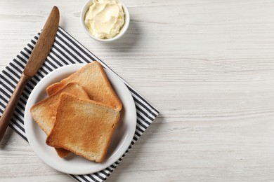 Photo of Delicious toasted bread slices with butter and knife on white wooden table, flat lay. Space for text