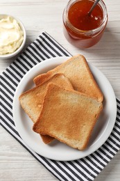 Photo of Delicious toasted bread slices served on white wooden table, flat lay