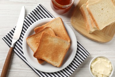 Photo of Delicious toasted bread slices served on white wooden table, flat lay