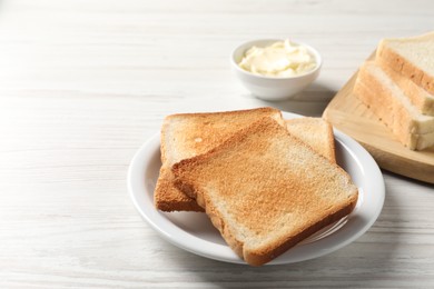 Photo of Delicious toasted bread slices on white wooden table