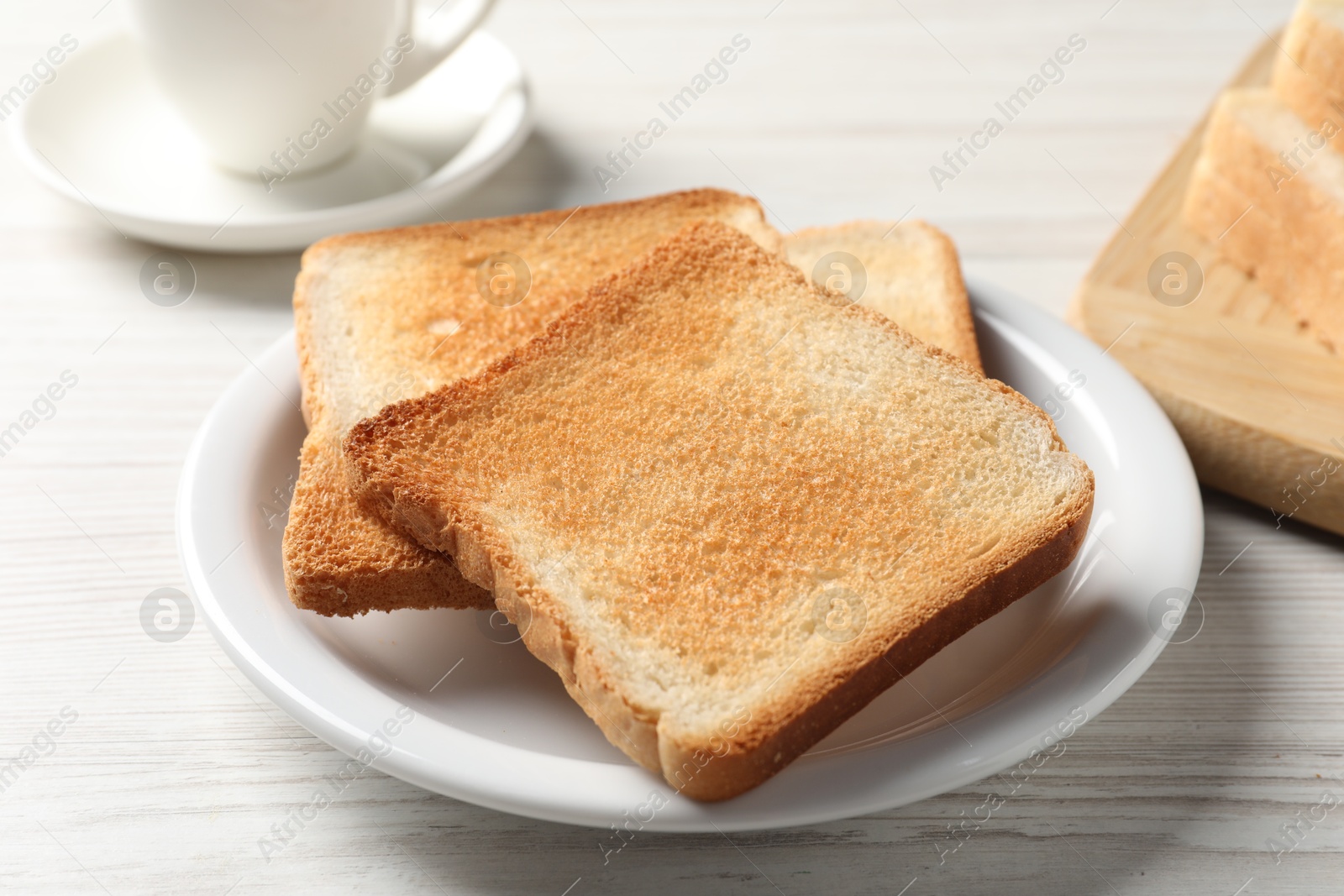 Photo of Delicious toasted bread slices on white wooden table, closeup