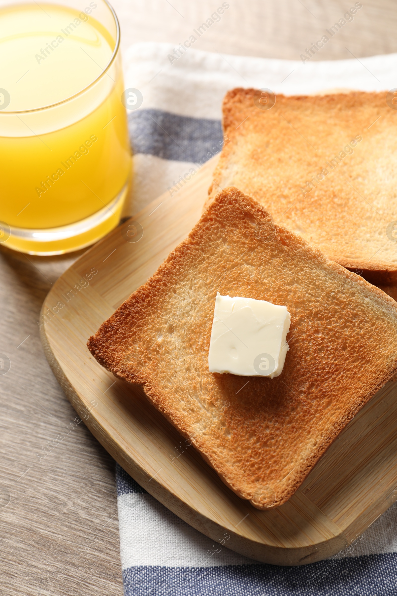 Photo of Delicious toasted bread slices with butter served on wooden table, above view