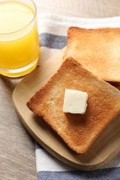 Photo of Delicious toasted bread slices with butter served on wooden table, above view