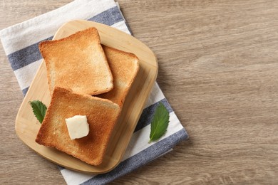 Photo of Delicious toasted bread slices with butter and mint on wooden table, top view. Space for text