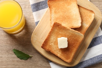 Photo of Delicious toasted bread slices with butter served on wooden table, flat lay