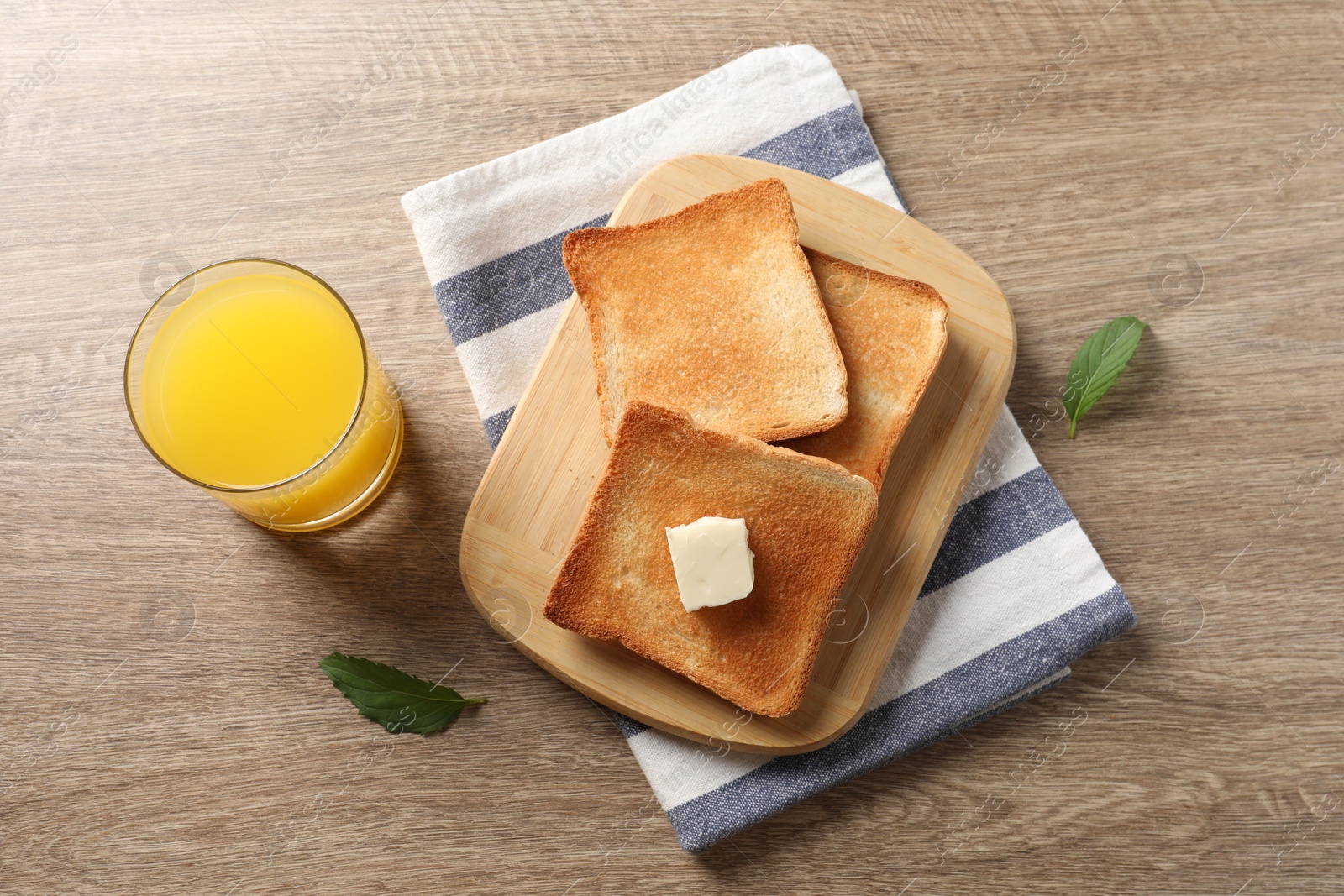 Photo of Delicious toasted bread slices with butter served on wooden table, flat lay